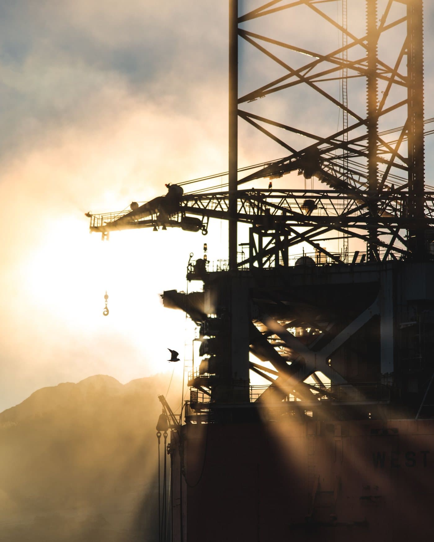 Drilling rig structure backlit at sunrise
